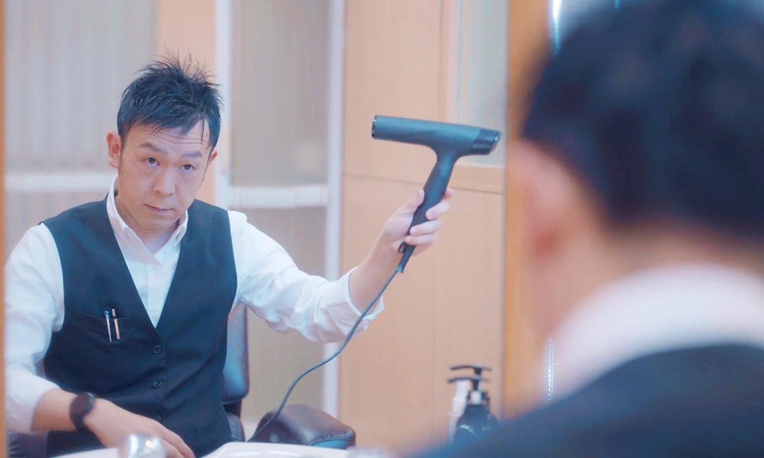 特徴2。ミライズを着用した男性が鏡の前でドライヤーをかけている写真。