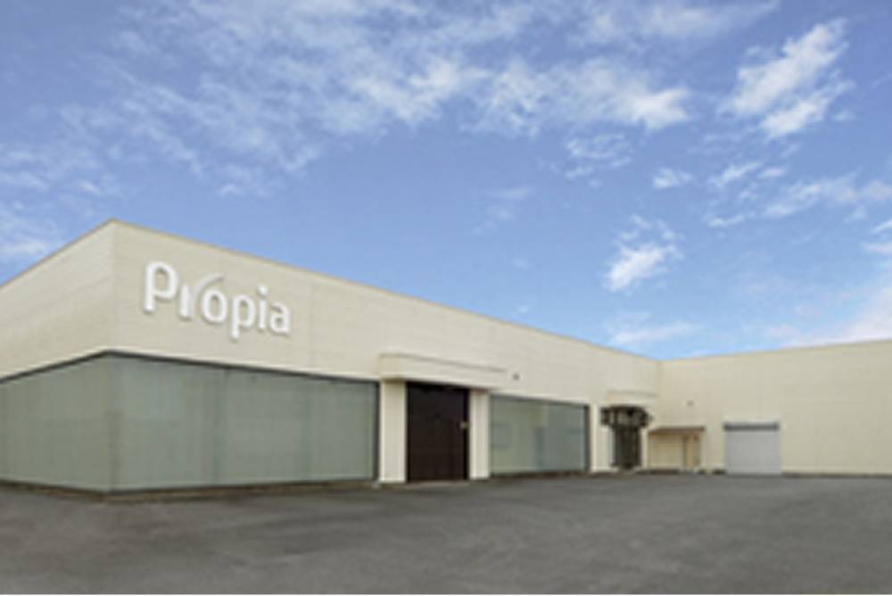 プロピアの自社工場の写真。青空の下に平屋建ての大きな工場が映っている。